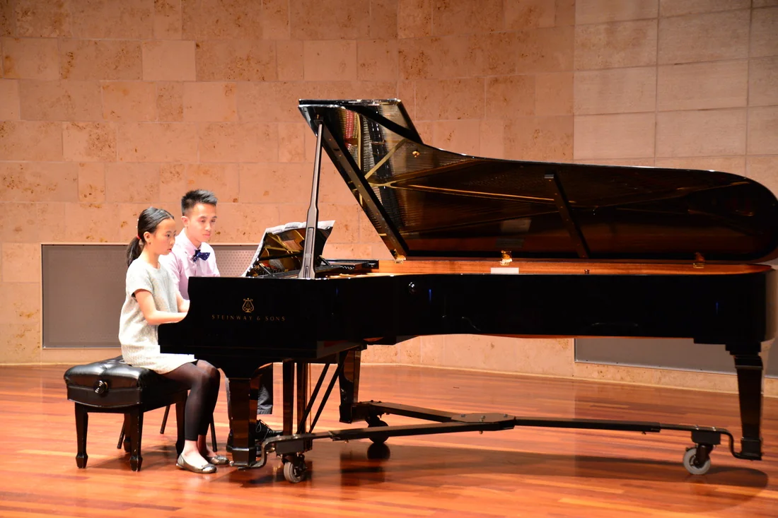 teacher guiding a piano student through a lesson